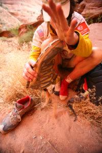 A racer empties sand from her shoe