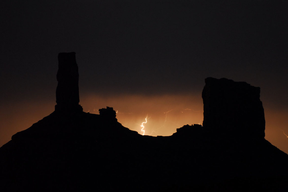 Lightning strikes in the dark between two desert rock formations