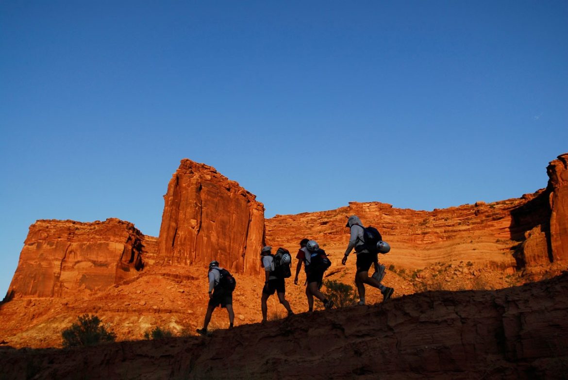 A team treks in front of redrocks